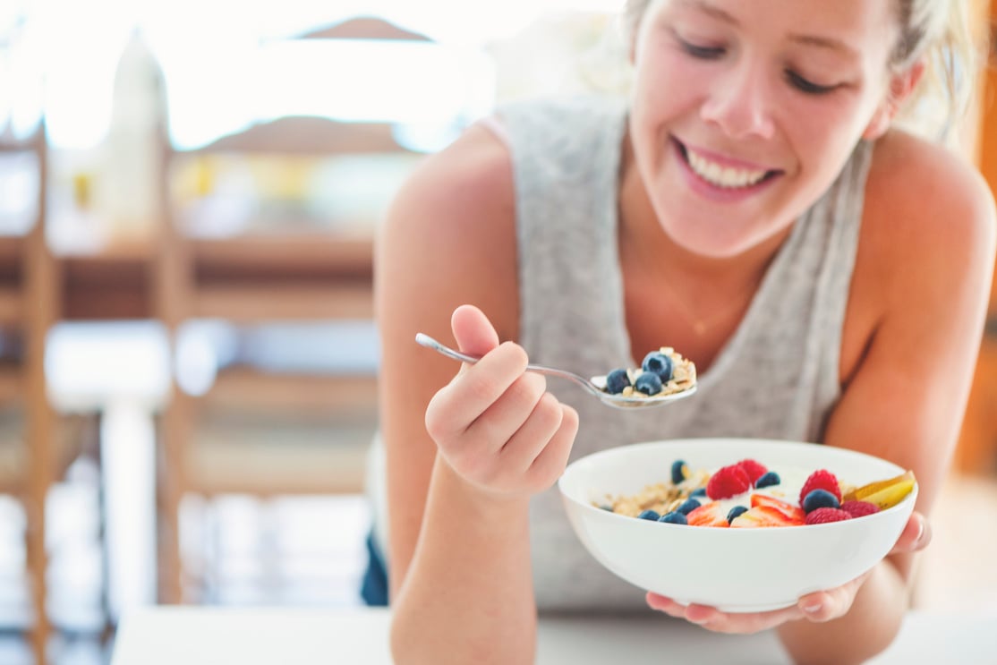 Happy woman Eating healthy breakfast bowl.